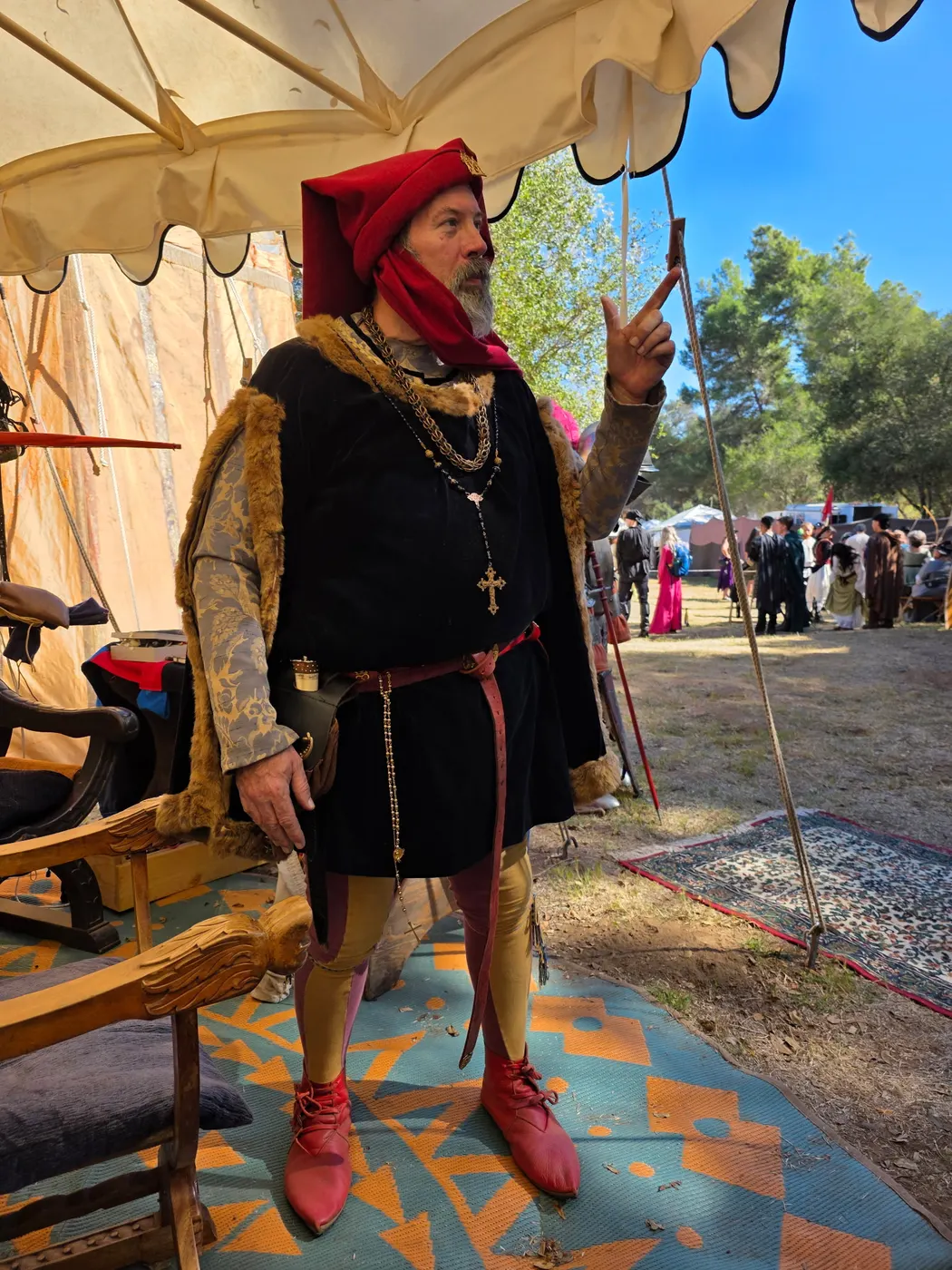 A reenactor in fifteenth-century dress: red chaperon hood, black doublet, gold chain and parti-colored hose